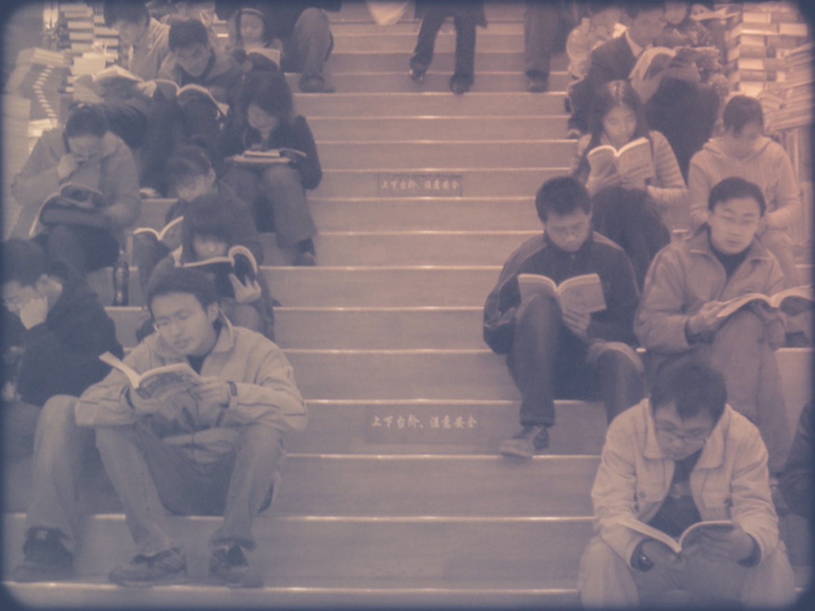 People sitting on bookstore steps, each absorbed in a book